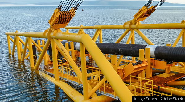 Laying of pipes with pipe-laying barge crane near the shore.