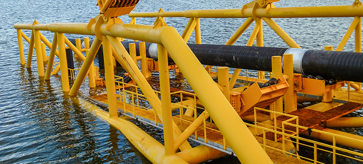 Laying of pipes with pipe-laying barge crane near the shore.